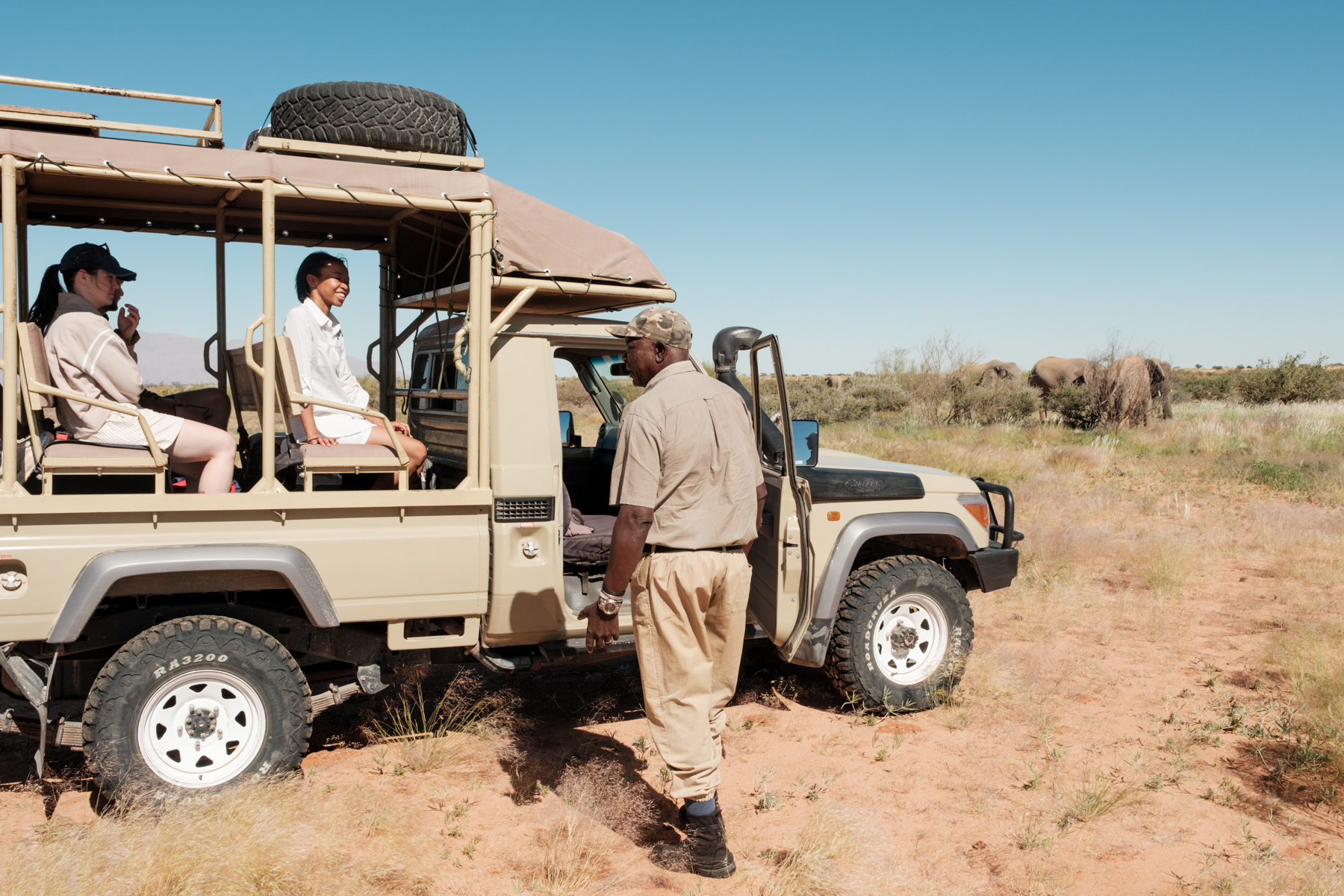 Guided safari vehicle with guests and desert elephants at Elephant Rest Tented Camp Damaraland